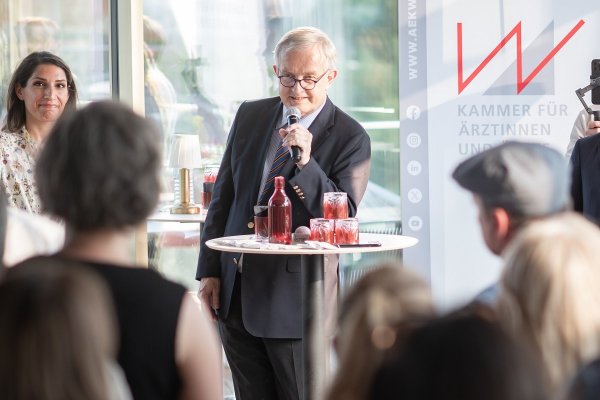 Mann im Anzug mit Mikrofon, an einem Stehtisch, bei der Eröffnung des Festes.