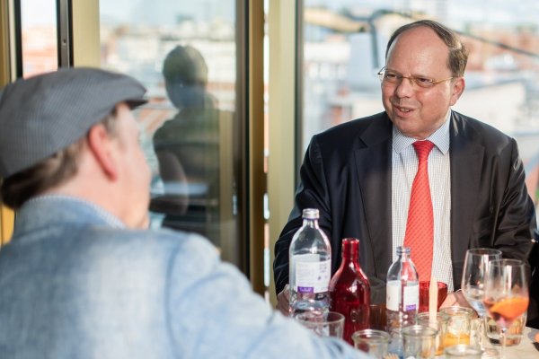 Zwei Männer im Gespräch an einem Stehtisch auf der Terrasse.