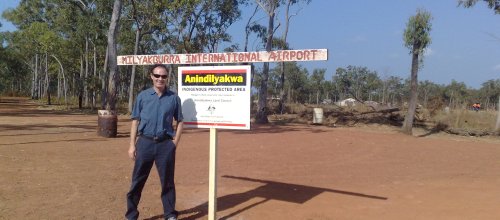 Ein Mann mit Sonnenbrille steht neben einem Straßenschild.