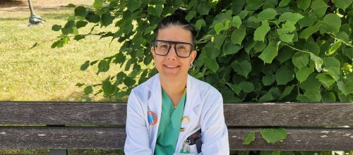 Mariam Vedadinejad in spitalsärztlicher Berufskleidung, auf einer Parkbank sitzend.