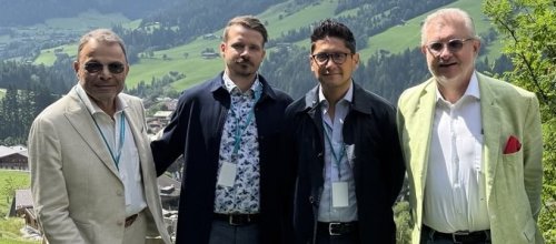 Vier Männer stehen im Freien in ländlicher Gegen beieinander und blicken in die Kamera.