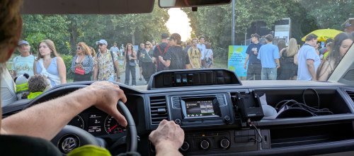 Aufnahme aus dem Auto heraus - man sieht aus der Windschutzscheibe hinaus auf eine Menge an Menschen, die vor und rund um das Einsatzfahrzeug stehen, wodurch das Fahrzeug nur im Schritttempo fahren kann.