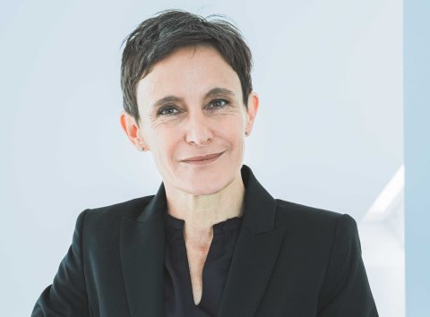 Frau im Blazer lächelt in die Kamera.