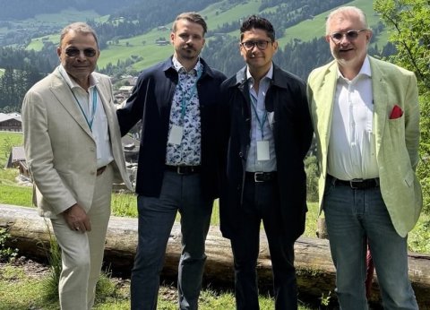 Vier Männer stehen im Freien in ländlicher Gegen beieinander und blicken in die Kamera.